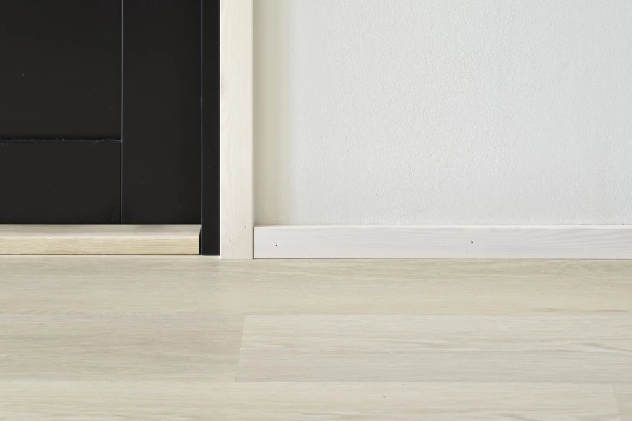Heller Vinylboden in Eichenoptik mit weißer Sockelleiste und dunkler Tür